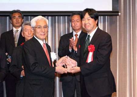 Mr. M. Ogasawara, President of ITU-AJ (left) presents the Achievement Award to Mr. M. Saitoh of NEC Corporation (right)
